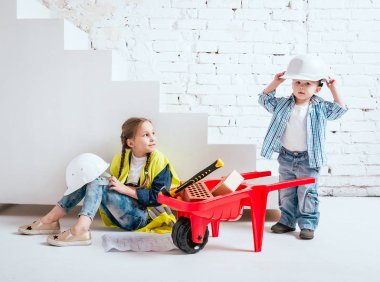 Örgüler ve onarım veya inşaat oynayan erkek kardeşi ile küçük kız