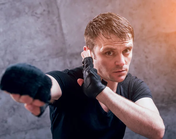 Young fighter posing in studio before grey wall