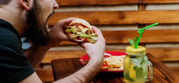 Genç adam yeme cheeseburger Restoran