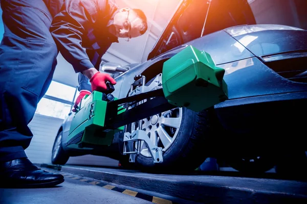 Araba tamircisi sensör süspansiyon ayarı sırasında yükleme. Tekerlek hizalama iş yerinde onarım servis istasyonu