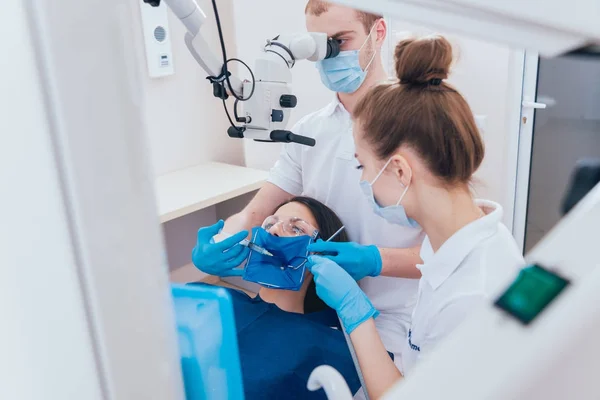 Treatment of root canals under a microscope, work with an assistant. Modern technology