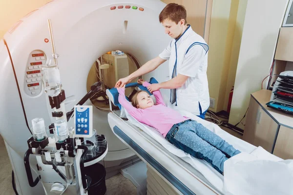 Medical equipment. Doctor and little girl patient in the room of computed tomography at hospital.