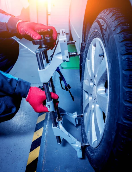Araba tamircisi sensör süspansiyon ayarı sırasında yükleme. Tekerlek hizalama iş yerinde onarım servis istasyonu