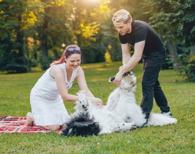 Genç çift yeşil park ile siyah ve beyaz Newfoundland köpek çalış
