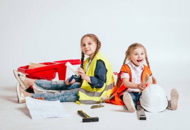 Onarım veya inşaat beyaz üzerinde oynarken örgüler ile iki küçük neşeli kız