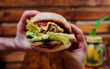 Büyük çizburger ve patates kızartması elinde. Restoran