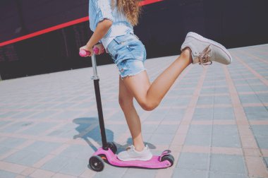 Güneşli bir gün, sokakta küçük kız sürme scooter
