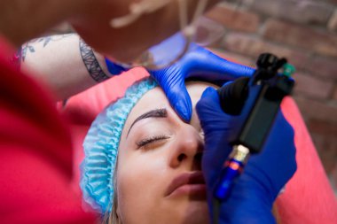 Profesyonel dövmeci kaş dövme bir kız yapar. Estetik tıp