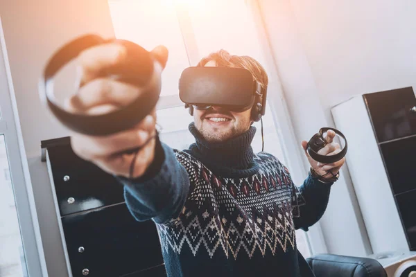 Mutlu genç adam ofiste bir oyun oynuyor. Sanal gerçeklik kulaklık.