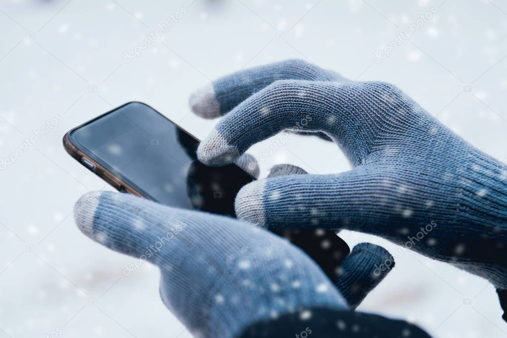 Man using smartphone with grey gloves for touch screens in winter