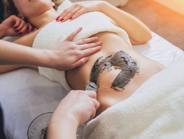 Kırpılmış görüntü kadının Spa'da rahatlatıcı. Çamur vücut masajı ile fırçalayın