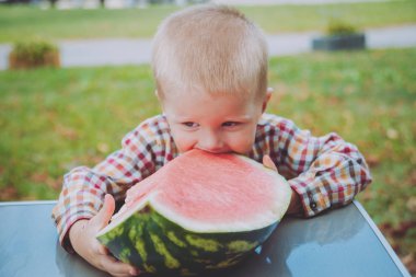 Küçük çocuk yeşil yaz parkta karpuz yeme