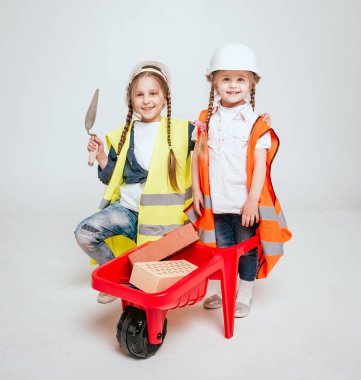 Onarım veya inşaat beyaz üzerinde oynarken örgüler ile iki küçük neşeli kız