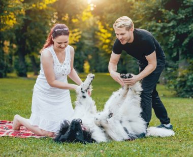 Genç çift yeşil park ile siyah ve beyaz Newfoundland köpek çalış