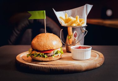 Ahşap masa üzerinde yangınları ile büyük ve lezzetli burger.