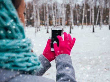 Smartphone ile pembe eldiven dokunmatik ekranlar için kışın kullanan kadın.
