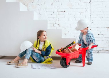 Örgüler ve onarım veya inşaat oynayan erkek kardeşi ile küçük kız