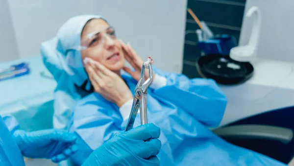 Dentist using surgical pliers to remove a decaying tooth.