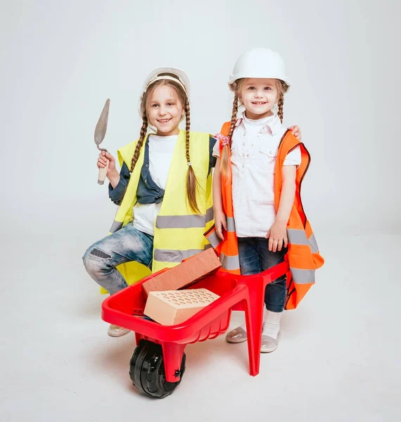 Onarım veya inşaat beyaz üzerinde oynarken örgüler ile iki küçük neşeli kız