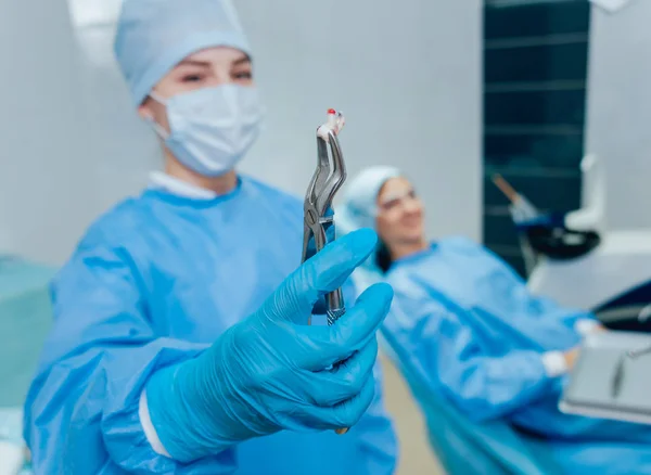 Dentist using surgical pliers to remove a decaying tooth. Modern dental clinic