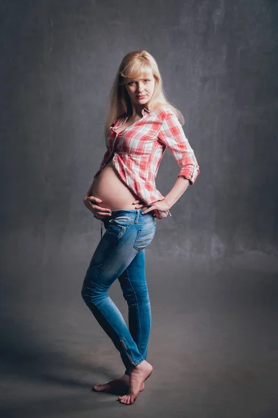 格子縞のシャツとブルー ジーンズの美しい金髪妊婦のスタジオ写真 — ストック写真