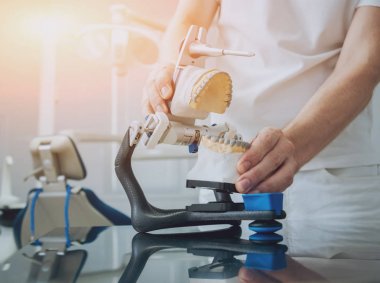 Diş teknisyeni, diş laboratuarında eklem makinesi ile çalışıyor.