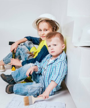 Örgüler ve onarım veya inşaat oynayan erkek kardeşi ile küçük kız