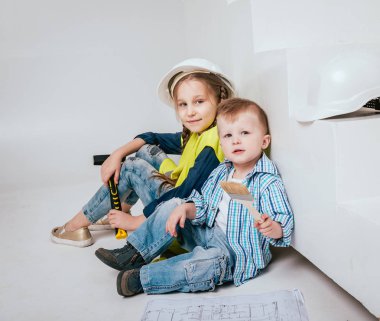 Örgüler ve onarım veya inşaat oynayan erkek kardeşi ile küçük kız