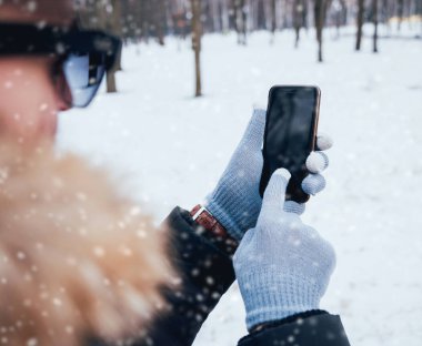 Smartphone ile gri eldiven dokunmatik ekranlar için kışın kullanan adam