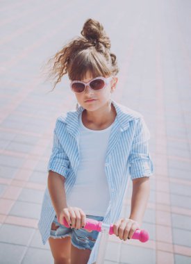 Güneşli bir gün, sokakta küçük kız sürme scooter