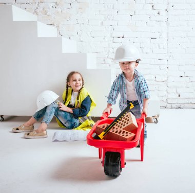 Örgüler ve onarım veya inşaat oynayan erkek kardeşi ile küçük kız