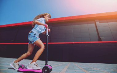 Güneşli bir gün, sokakta küçük kız sürme scooter