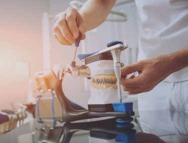 Diş teknisyeni, diş laboratuarında eklem makinesi ile çalışıyor.