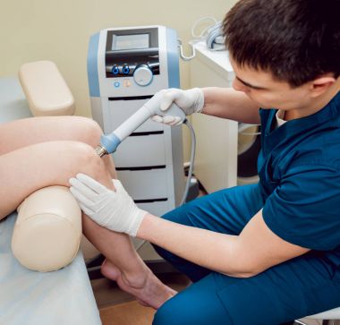 Şok dalga tedavisi. Manyetik alan, rehabilitasyon. Fizyoterapist doktor ameliyat bir hastanın diz üzerinde gerçekleştirir.