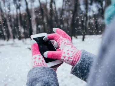 Smartphone ile pembe eldiven dokunmatik ekranlar için kışın kullanan kadın.
