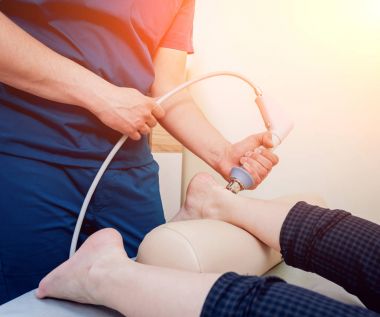 Şok dalga tedavisi. Manyetik alan, rehabilitasyon. Fizyoterapist doktor ameliyat bir hastanın topuk üzerinde gerçekleştirir.
