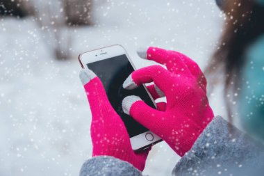 Smartphone ile pembe eldiven dokunmatik ekranlar için kışın kullanan kadın.