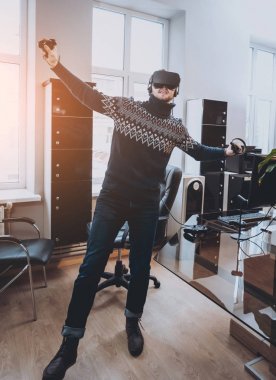 Mutlu genç adam ofiste bir oyun oynuyor. Sanal gerçeklik kulaklık.