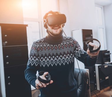 Mutlu genç adam ofiste bir oyun oynuyor. Sanal gerçeklik kulaklık.