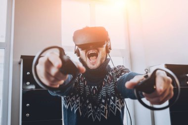 Mutlu genç adam ofiste bir oyun oynuyor. Sanal gerçeklik kulaklık.