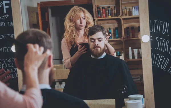 Master cuts hair and beard of men, hairdresser makes hairstyle for a young man. Hipsters