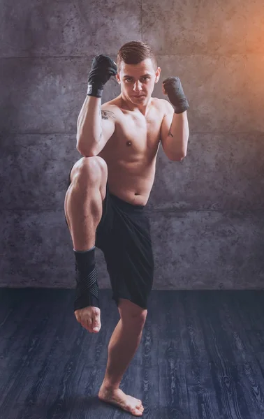 Young fighter posing in studio before grey wall