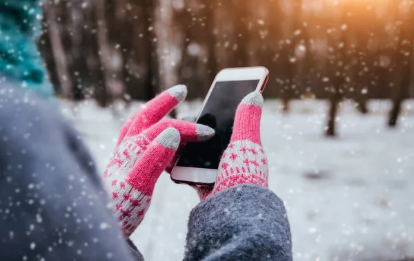 Woman using smartphone with pink gloves for touch screens in winter.
