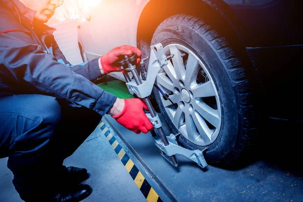 Araba tamircisi sensör süspansiyon ayarı sırasında yükleme. Tekerlek hizalama iş yerinde onarım servis istasyonu