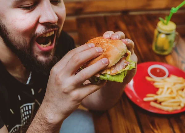 Genç adam yeme cheeseburger Restoran