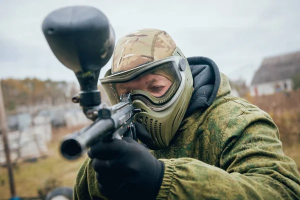 Man with gun playing at paintball. Outdoors.