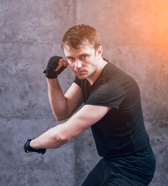 Young fighter posing in studio before grey wall