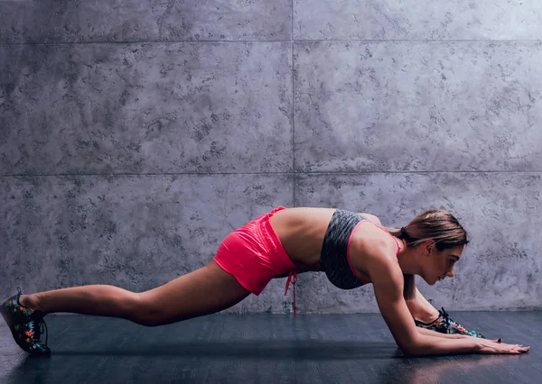 Studio poz ve farklı egzersizleri yapıyor genç atletik beyaz kadın.