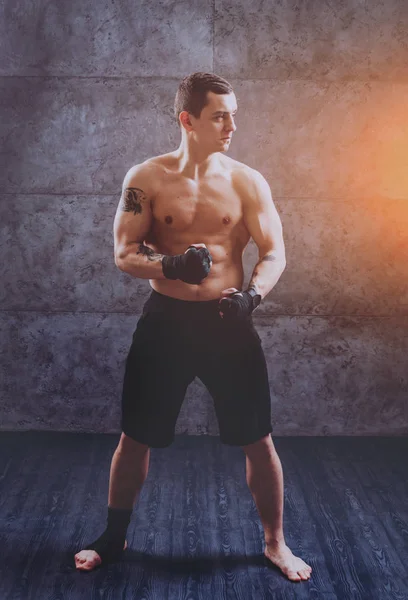 Young fighter posing in studio before grey wall