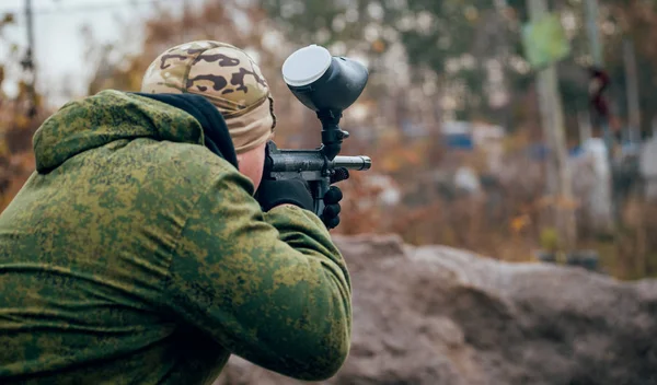 Man with gun playing at paintball. Outdoors.